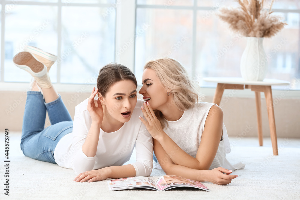 Young woman telling her sister secret at home Young woman telling her sister secret at home