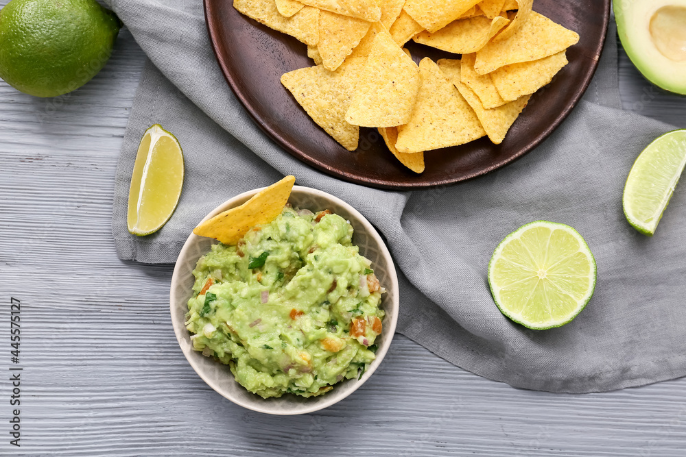Bowl with tasty guacamole and nachos on color wooden background Bowl with tasty guacamole and nachos on color wooden background