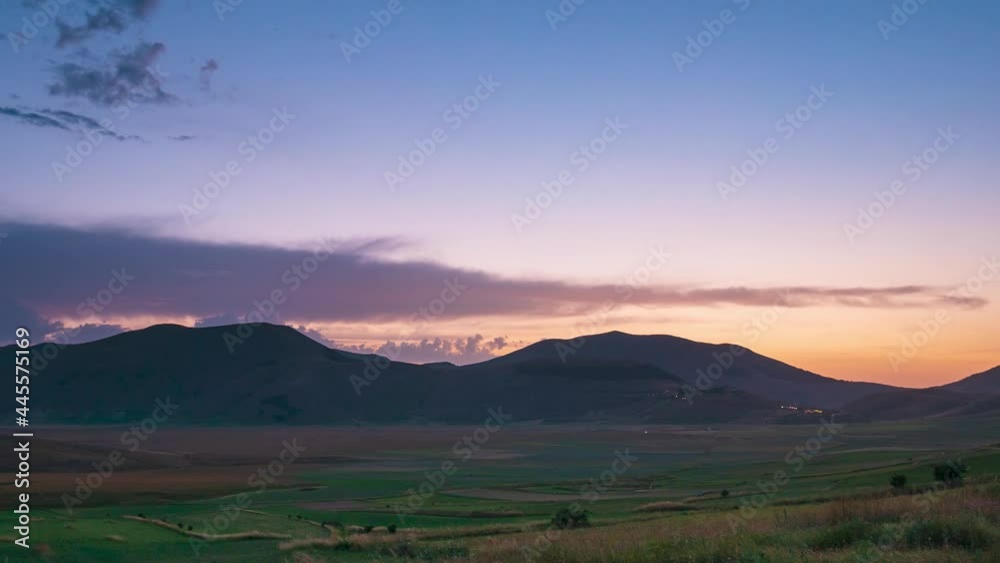 Time lapse: sunset over Castelluccio di Norcia highlands, Italy. The village perched on hill top over blooming agriculture fields, the famous colourful flowering plain in the Apennines Time lapse: sunset over Castelluccio di Norcia highlands, Italy. The village perched on hill top over blooming agriculture fields, the famous colourful flowering plain in the Apennines