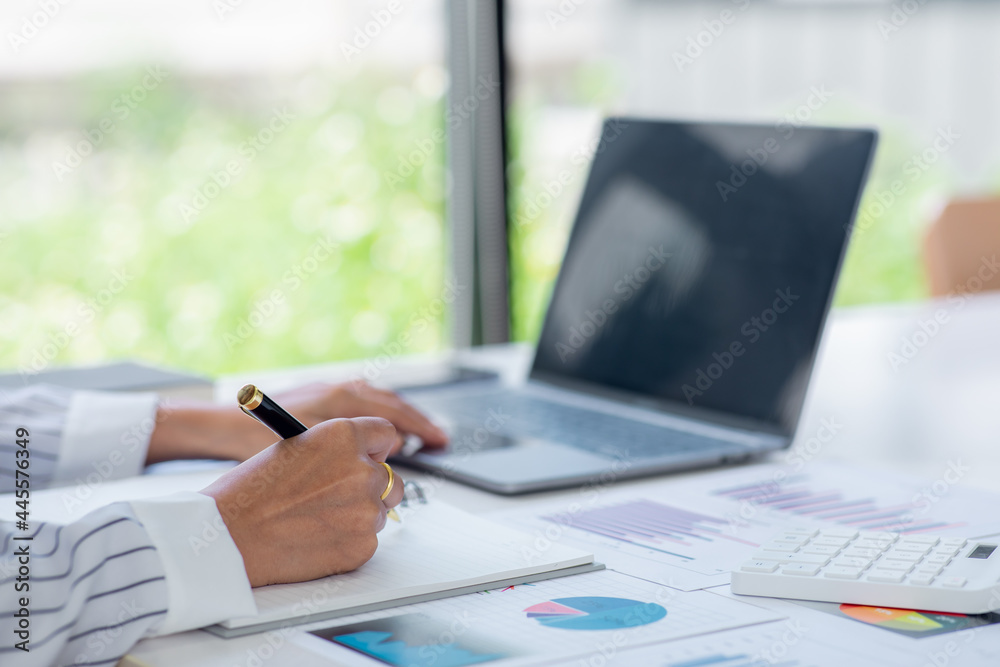 Close uo of Business woman analyst working - hand with pen,computer laptop calculator, magnifier, worksheet analysis report data charts and graph,Finance concept. Close uo of Business woman analyst working - hand with pen,computer laptop calculator, magnifier, worksheet analysis report data charts and graph,Finance concept.
