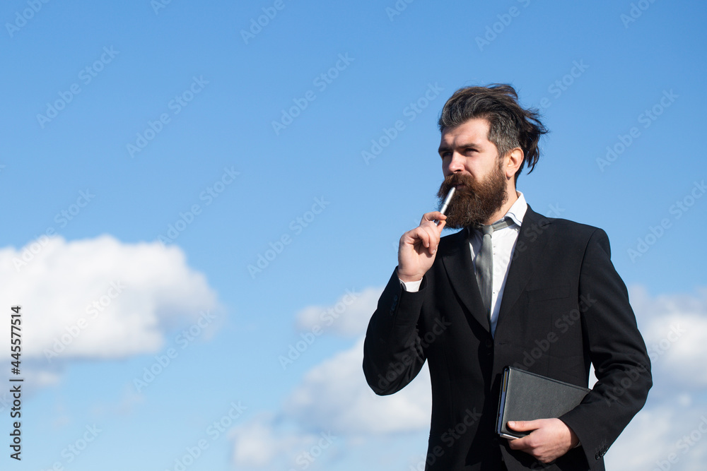 Business man with sky. Business man is thinking about something with pencil. Business dreams. Thoughtful young man in shirt and tie holding note pad and pen. Business man with sky. Business man is thinking about something with pencil. Business dreams. Thoughtful young man in shirt and tie holding note pad and pen.