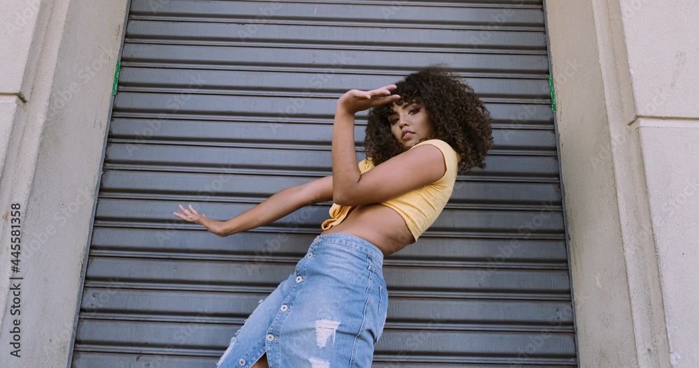 Modern style dancer with afro on her head dancing on street Modern style dancer with afro on her head dancing on street