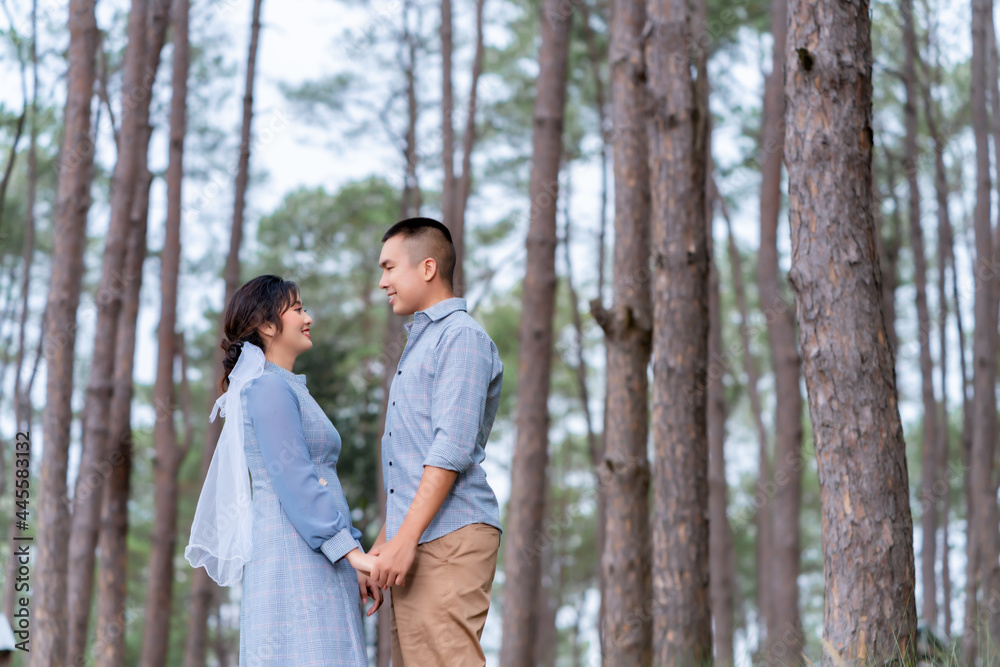 Portrait of an Asian couple posing for a pre-wedding photo in identical blue outfits, happily showing off their expressions of love in a pine garden. Portrait of an Asian couple posing for a pre-wedding photo in identical blue outfits, happily showing off their expressions of love in a pine garden.