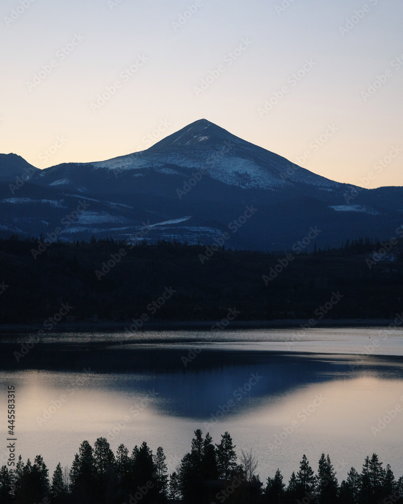 epic mountain during winter with snow on peak and lake in foreground