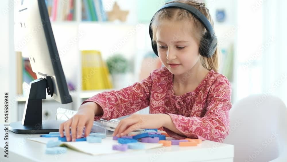 Primary school girl learning numbers during distant lesson via computer webcam Primary school girl learning numbers during distant lesson via computer webcam