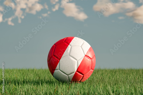 Soccer ball with the national colors of Austria on a green meadow. Leather in slightly used look. Background blue with clouds. 3D illustration.