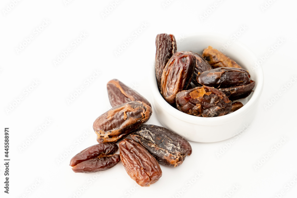 Fresh dates in a small white bowl on a white surface. Concept healthy and natural food