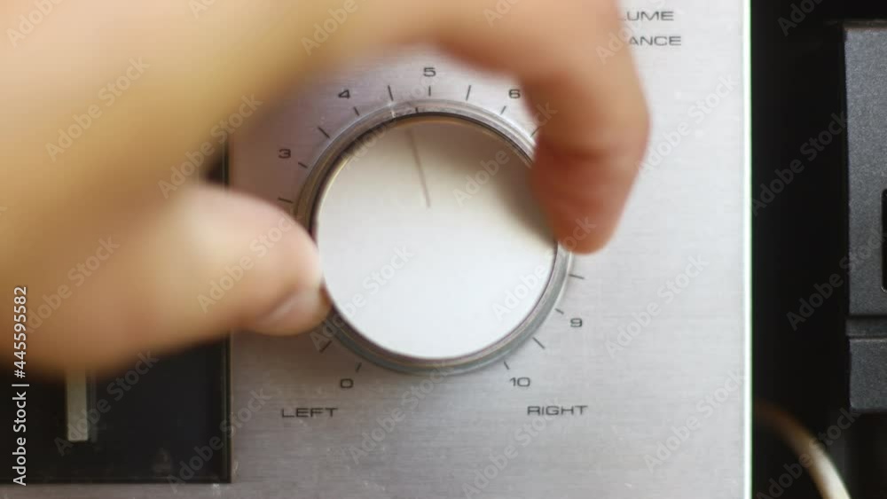 Close up of hand turning a volume knob on home stereo unit	

