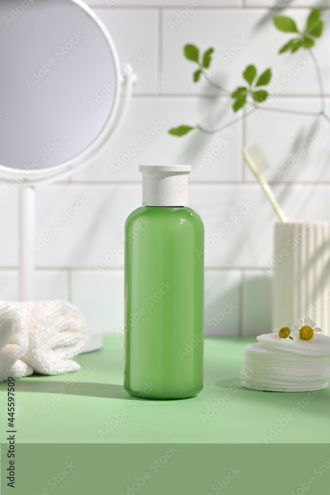 Balancing skin bottle green with white cotton towel in the bathroom. 