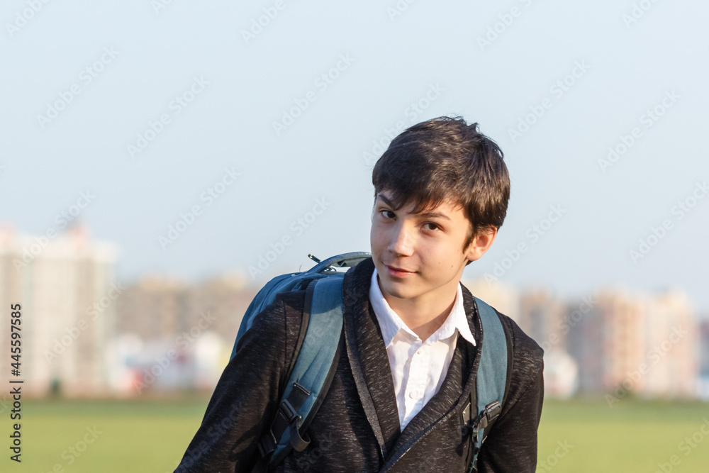 School teenager waiting for a school bus, on his way to school. On the way home from school against the background of the urban landscape School teenager waiting for a school bus, on his way to school. On the way home from school against the background of the urban landscape