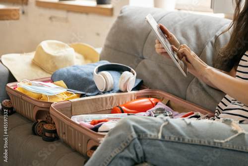 Close-up female hands packing suitcase for summer vacation, holiday at home interior, indoors. Concept of fashion, beauty, lifestyle, lesuire activity.