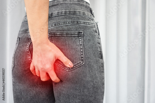 woman hand scratching her itchy  buttocks because of wearing too tight jeans photo