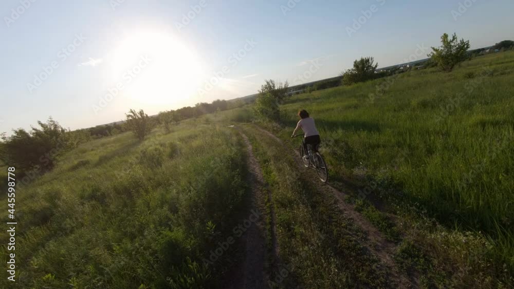 Adult wman riding bike in the field on the nature in sunset time. Female person with bicycle spending time outdoors. Healthy leisure and activity Adult wman riding bike in the field on the nature in sunset time. Female person with bicycle spending time outdoors. Healthy leisure and activity