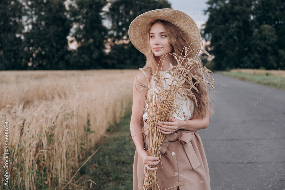 Obraz premium a beautiful girl with long brown hair in a field with ears of wheat