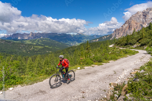 pretty active senior woman riding her electric mountain bike up to Valparola Pass in the Alta Badia Dolomites , South Tirol and Trentino, Italy © Uwe