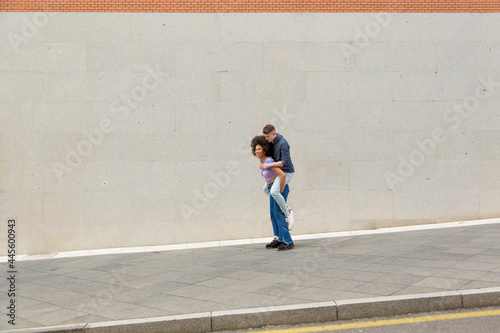 woman carrying man on her back in the street wearing blue casual clothes