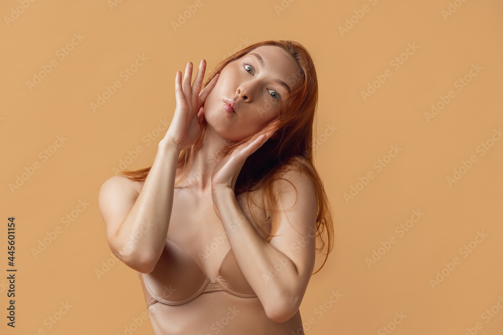 Young beautiful woman in lingerie posing isolated over sand color studio back ground. The fitness, diet, sports, natural beauty and aesthetic cosmetology concept. Young beautiful woman in lingerie posing isolated over sand color studio back ground. The fitness, diet, sports, natural beauty and aesthetic cosmetology concept.