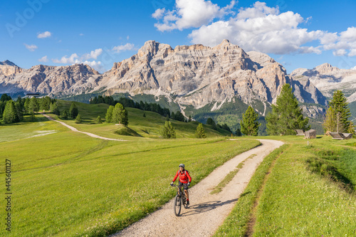 nice and active senior woman riding her electric mountain bike on the Pralongia Plateau in the Alta Badia Dolomites with awesome Sasso die Santa Cruce summit in Backg, South Tirol and Trentino, Italy © Uwe