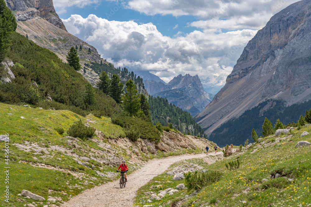 pretty active senior woman riding her electric mountain bike in the Fanes high Valley, part of Fanes-Sennes-Braies nature park in the Alta Badia Dolomites,  South Tirol and Trentino, Italy
