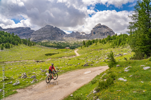 pretty active senior woman riding her electric mountain bike in the Fanes high Valley, part of Fanes-Sennes-Braies nature park in the Alta Badia Dolomites, South Tirol and Trentino, Italy 