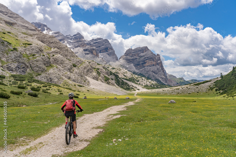 pretty active senior woman riding her electric mountain bike in the Fanes high Valley, part of Fanes-Sennes-Braies nature park in the Alta Badia Dolomites,  South Tirol and Trentino, Italy
