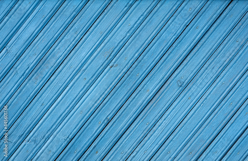 An old blue-painted wall made of planks laid on an oblique diagonal. Wooden natural time-aged background