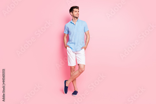 Full length body size photo smiling man in blue shirt white shorts looking copyspace isolated pastel pink color background © deagreez