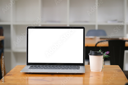 Mock up with blank screen of laptop computer and cup of coffee on the wooden desk in cafe.