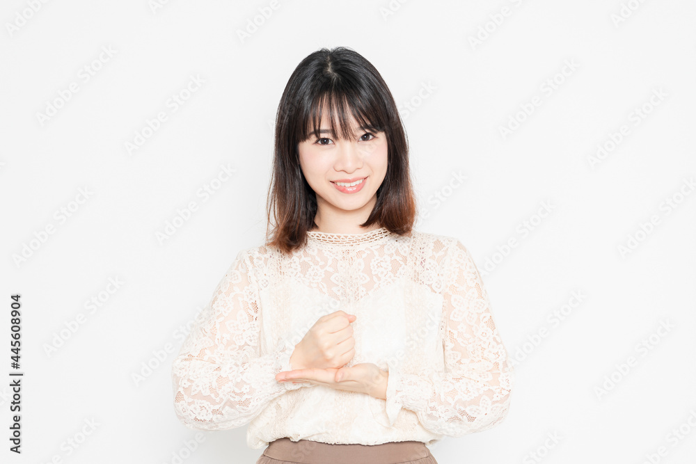 白背景の前に立って、納得のジェスチャーをする、レースのブラウスを着た若い女性 白背景の前に立って、納得のジェスチャーをする、レースのブラウスを着た若い女性