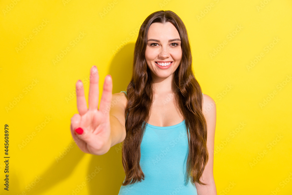 Photo of optimistic brunette hairdo young lady show three fingers wear teal top isolated on vivid yellow color background