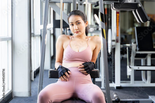 Beautiful fitness slim fit woman in sportswear sitting take a break on fitness machine in a gym room , Asian sexy girl slim body - lifestyle Healthy woman fitness concept