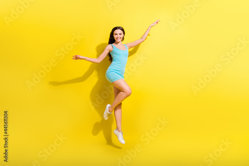 Full length photo of joyful brunette hairdo young lady jump wear teal dress isolated on vivid yellow color background