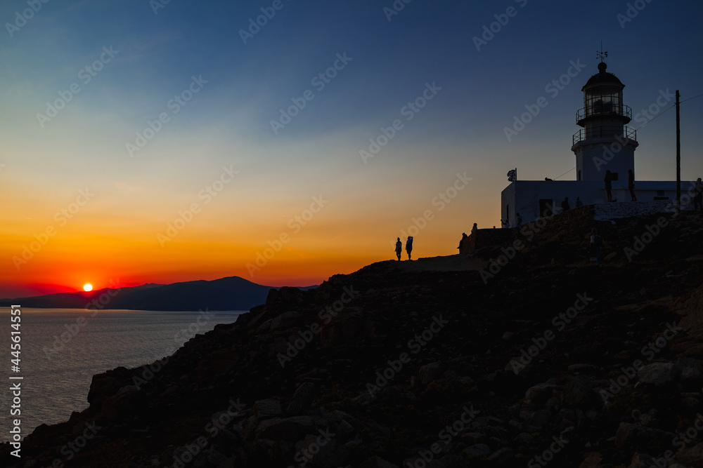 Silhouette of a lighthouse during orange sunset in Mykonos, Greece