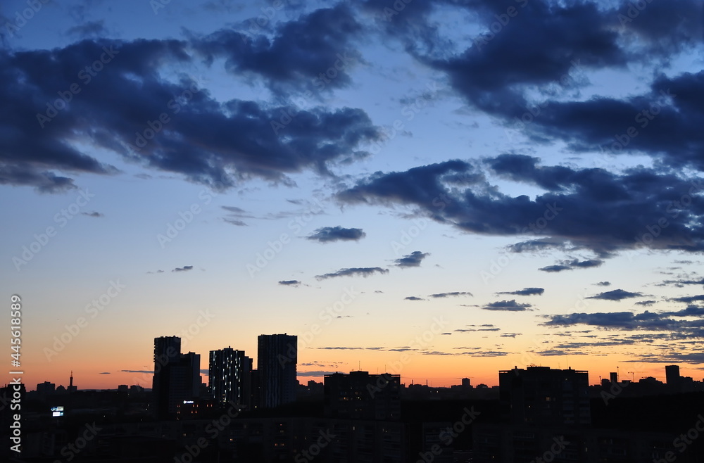 Dark city buildings at dusk and dramatic clouds hanging over them. Dark city buildings at dusk and dramatic clouds hanging over them.