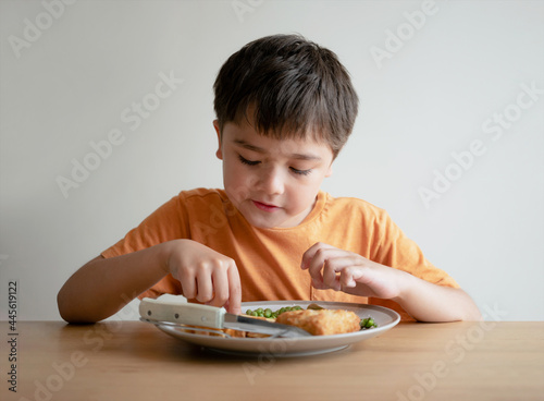 Portrait of 7-8 year old kid boy having homemade fish finger and french fries for Sunday dinner at home, A happy child eating lunch, Children eating heathy and Fresh food, Healthy life style concept photo