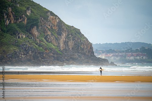 People walking with surfboards and surfing, in the city of Somo in the province of Santander, Spain, near large cliffs and virgin beaches photo