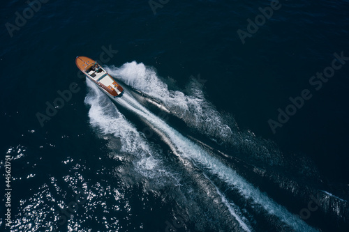 Top view of a wooden powerful motor boat. Luxurious wooden boat fast movement on dark water. Classic Italian wooden boat fast moving aerial view.