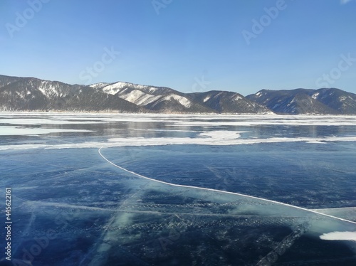 transparent ice of a lake in winter among snow-capped mountains