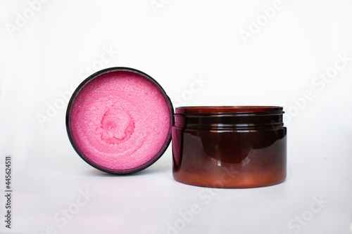 pink body scrub in brown jar on white background