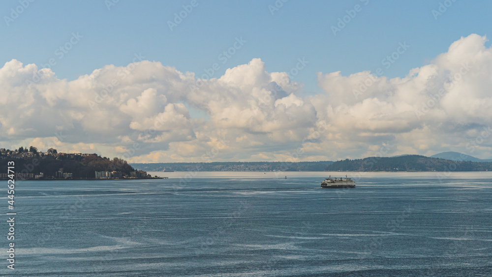 Washington Ferry sails on Elliot Bay past West Seattle and Cloud sky background