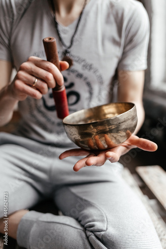 A young male yogi playing a musical instrument a Tibetan singing bowl