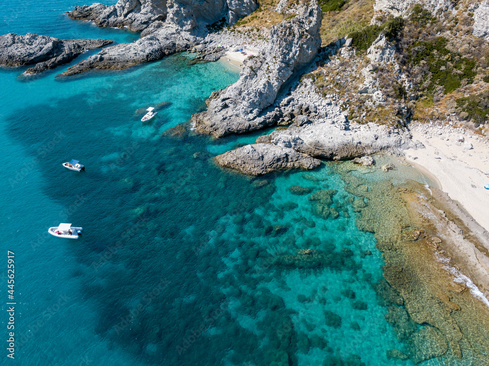 Aerial view of moored boats floating on a transparent sea. Scuba diving and summer holidays. Capo Vaticano, Calabria, Italy. Promontory.
