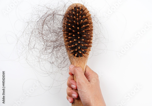 A woman's hand grabs the missing hair on the brush, isolated on white background. hair loss. 