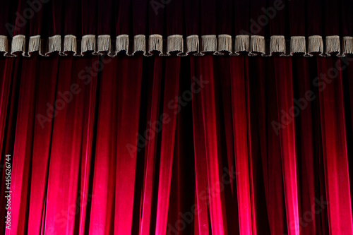 Red curtain on the theater stage, illuminated by spotlights. Intermission between performances.