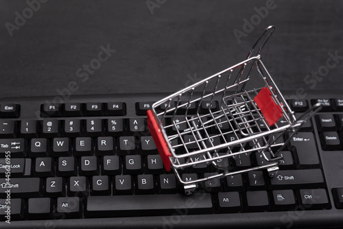 Keyboard and small shopping cart close up. Online shopping concept. Supermarket trolley