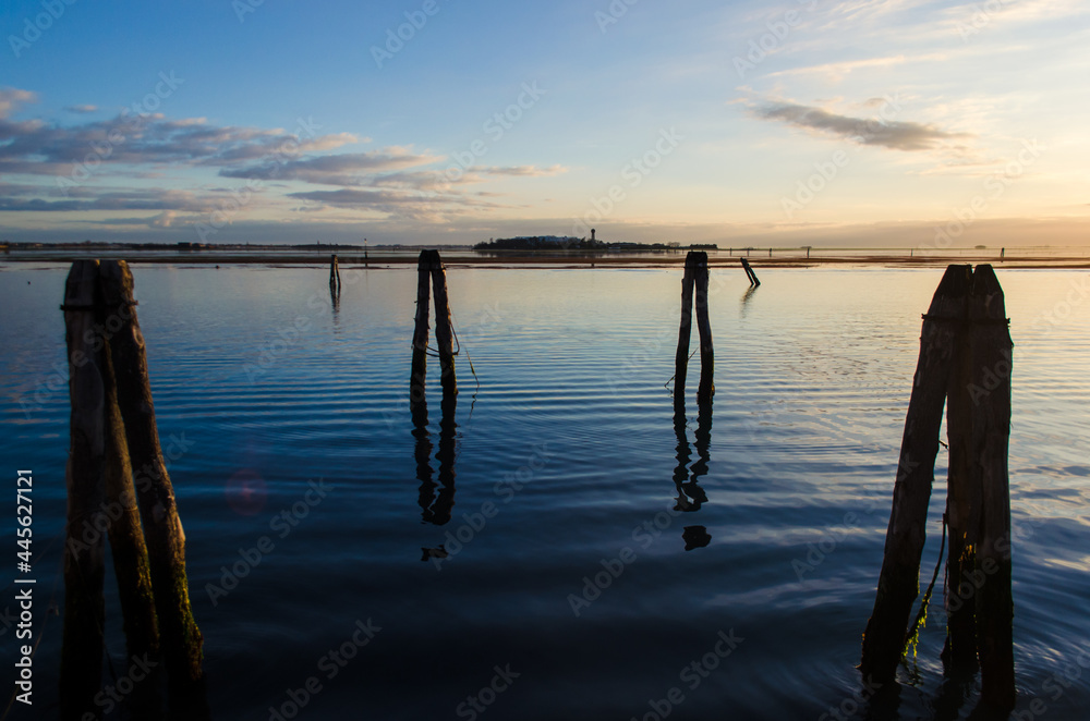 La sagoma di alcune briccole, tipici pali di legno della laguna di Venezia, si stagliano sulla luce del crepuscolo La sagoma di alcune briccole, tipici pali di legno della laguna di Venezia, si stagliano sulla luce del crepuscolo