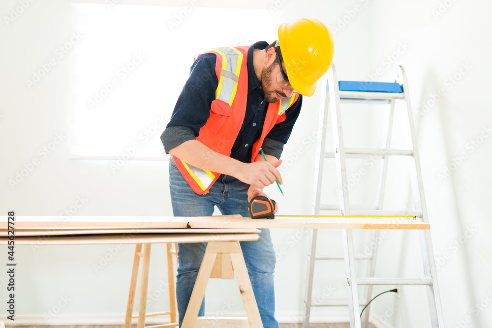 Male engineer using a measuring tape to cut wood Male engineer using a measuring tape to cut wood