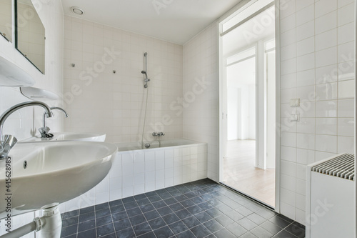 Tiled restroom with bathtub, sinks and doorless entrance photo