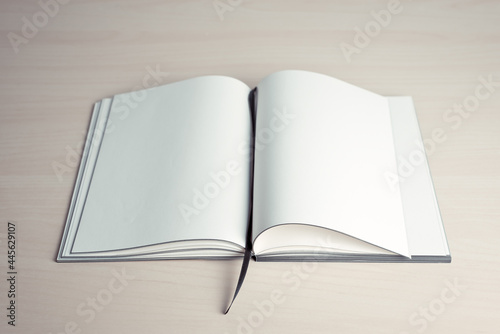 Opened book with blank pages on top of wooden table