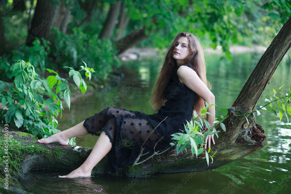A beautiful young cheerful girl with long flowing hair in a black long ...